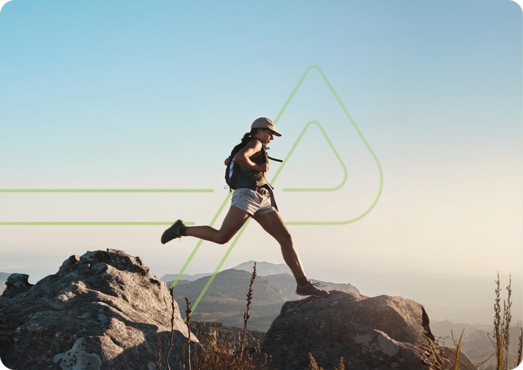 brand-identity-two-col-img-3 | HIFI Agency | Financial Marketing Agency Woman hiking and leaping between rocks on a mountaintop at sunrise with a backpack.