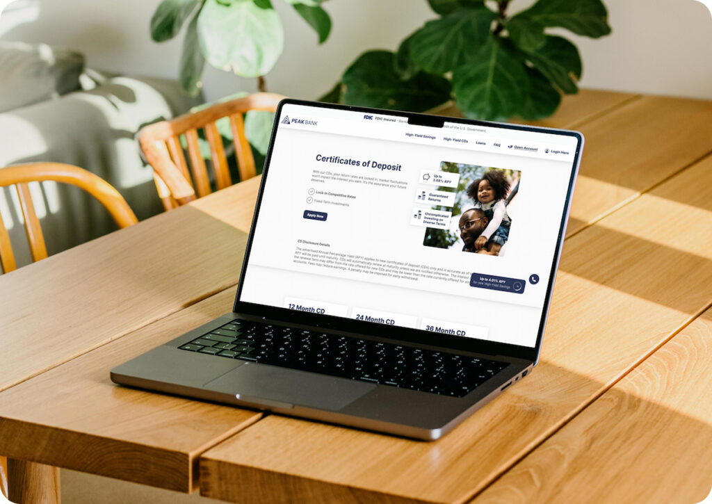 digital-product-experience-two-col-img-1 | HIFI Agency | Financial Marketing Agency Laptop on a wooden table showing a banking site about Certificates of Deposit, in a sunlit room with green plants in the background.